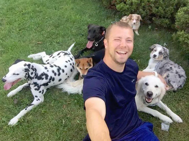 Lee Seibold on the grass with a group of relaxed, well-behaved dogs, including his Dalmatian Remy