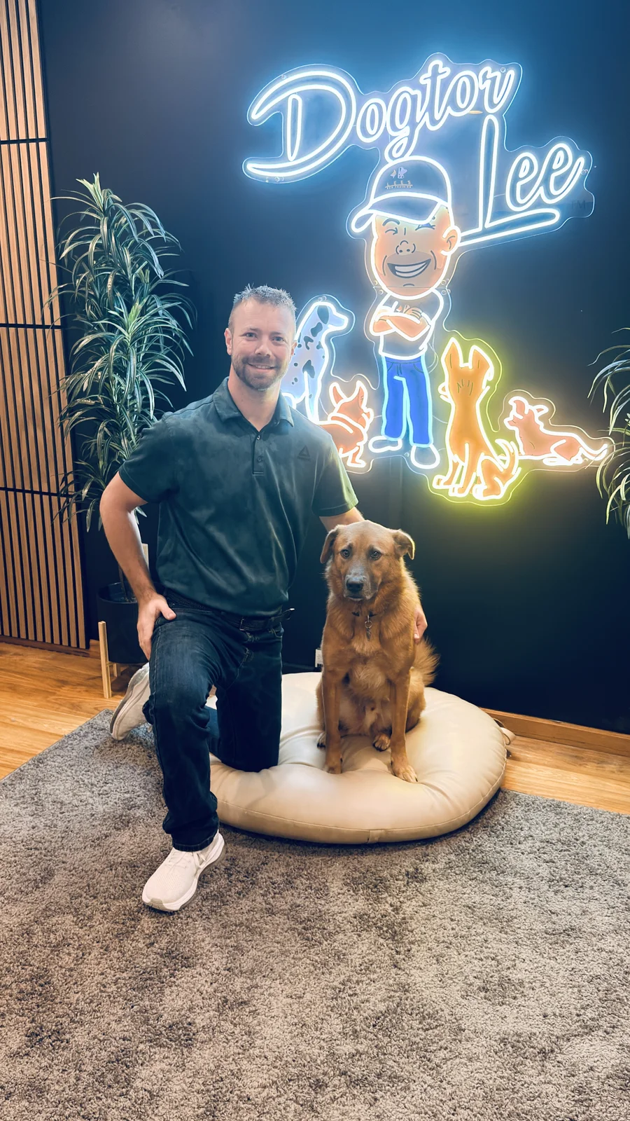 Lee Seibold with a dog at his Huntington, IN training facility, under the Dogtor Lee neon sign