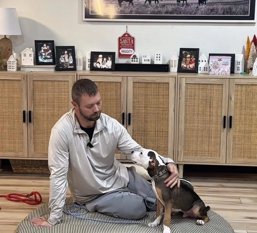 Lee Seibold sitting on the floor with a young dog during an in-home training session